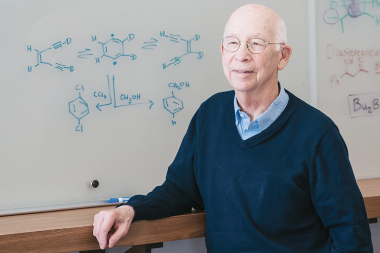 Robert Bergman standing in front of a white board with equations on it.
