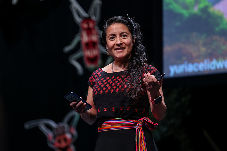 Yuria Celidwen speaking on a stage giving a presentation