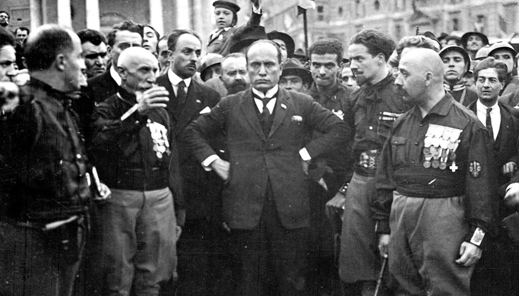 Italian fascist leader Benito Mussolini, center, in a suit and tie, surrounded by leaders of his Black Shirt militia in 1922