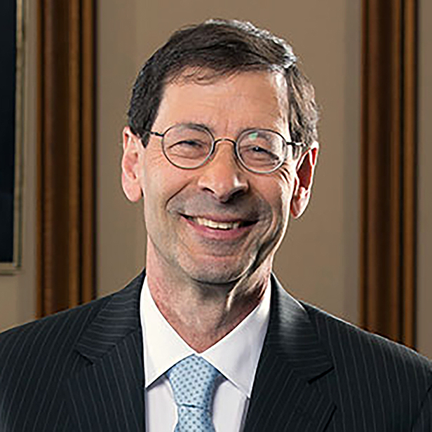 Maurice Obstfeld in a coat and tie, standing against an ornate background