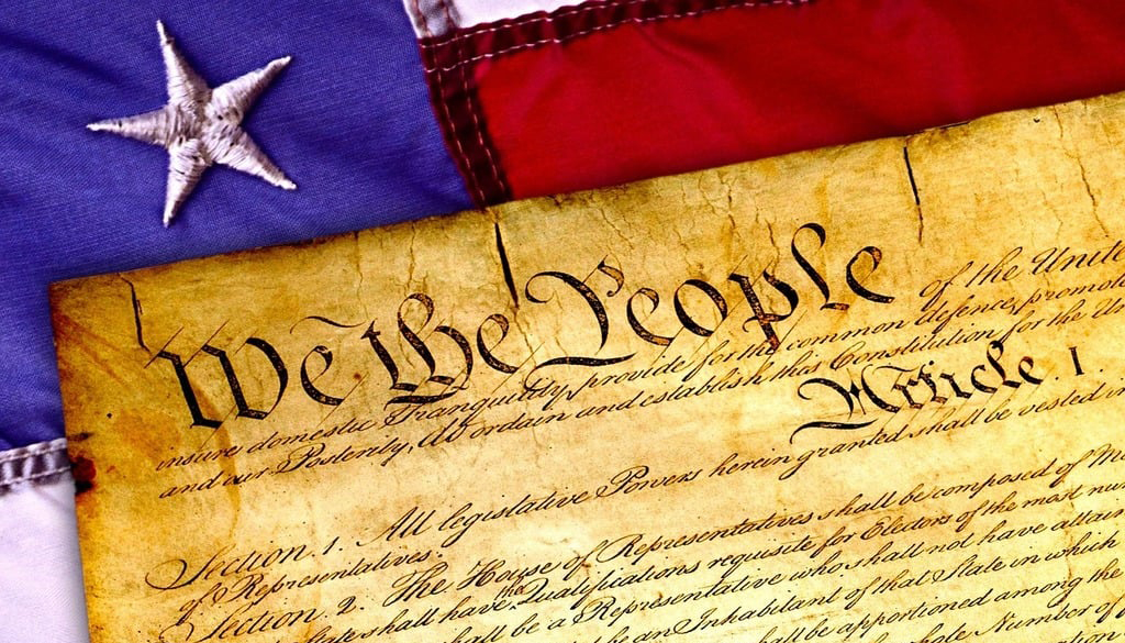 A closeup of the U.S. Constitution resting atop an American flag.
